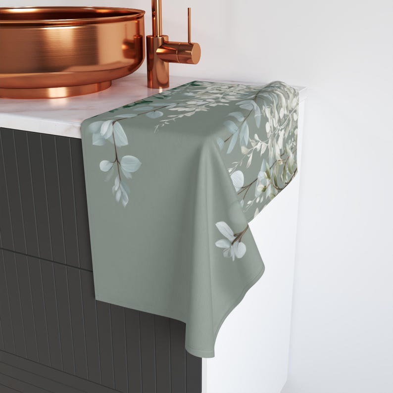 a bathroom sink with a copper-colored basin and a green towel with a floral pattern hanging on the side of the sink.