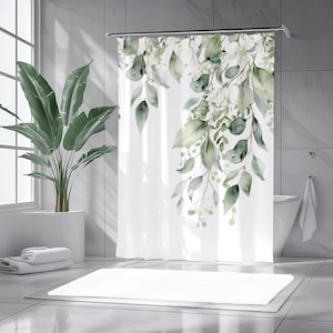 Puede incluir: Cortina de ducha blanca con un diseño de acuarela de hojas verdes y grises y flores blancas. El patrón botánico cae en cascada por el lado derecho. La cortina está en un baño moderno.