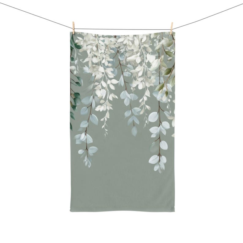 A green towel with a white floral pattern hanging on a clothesline.