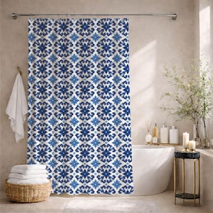 May include: A shower curtain featuring a repeating geometric pattern in shades of dark blue and light blue on a white background. The design consists of symmetrical floral-like motifs arranged in a grid, suspended from a silver metal rod.