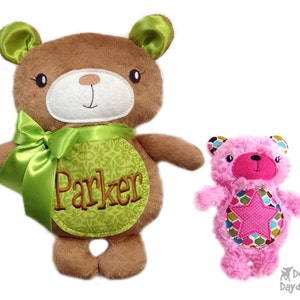 Puede incluir: Dos osos de peluche, uno marrón con un lazo verde y el nombre "Parker" bordado en el pecho, y otro rosa con un parche en forma de estrella en el pecho.