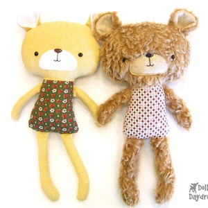 Pode incluir: Dois brinquedos de pelúcia feitos à mão, um urso amarelo e marrom e um urso marrom com textura felpuda. Ambos os ursos usam vestidos com padrões florais.