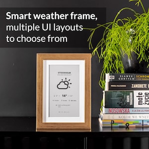 May include: A smart weather frame with multiple UI layouts to choose from. The frame is rectangular with a gold-colored border and a white interior. The display shows weather information, including temperature in Fahrenheit and Celsius.