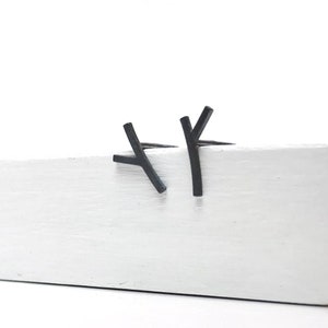 May include: A pair of black minimalist earrings in the shape of a Y. The earrings are made of metal and are simple and modern.
