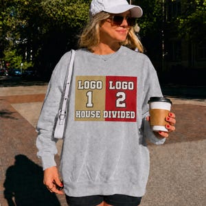 May include: A heather gray crewneck sweatshirt featuring a rectangular graphic divided into a gold left side and a red right side. The text reads "LOGO 1" above "HOUSE" on the left, and "LOGO 2" above "DIVIDED" on the right in white block letters.