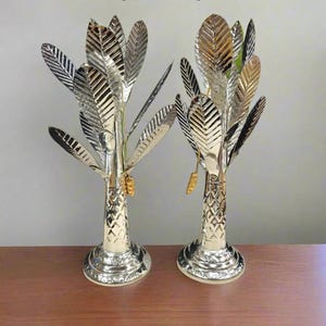 Puede incluir: Una taza de cerámica blanca con asa negra y el texto "But First, Coffee" en negrita negra. La taza se encuentra sobre un fondo borroso, sugiriendo un ambiente acogedor.