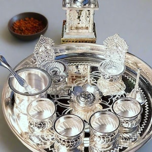 Puede incluir: Un juego de ofrendas religiosas de color plateado, que incluye un templo decorativo, pequeñas tazas y una bandeja de servicio. El juego también incluye un pequeño cuenco con contenido naranja-marrón y el texto "STYLE 1".