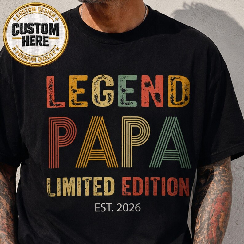 May include: Black t-shirt with the words "LEGEND PAPA LIMITED EDITION EST. 2026" in retro-style lettering. The design includes a circular "CUSTOM DESIGN" patch. The shirt is a vintage-inspired gift.