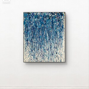 May include: Abstract art painting in a black frame. The artwork features a vertical composition of blue and white paint strokes, creating a textured, dripped effect. The colour palette includes shades of blue, with hints of purple and white, against a cream-coloured background.