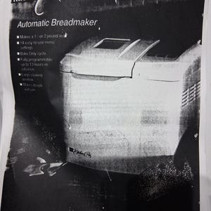 May include: Black and white image of a Regal Kitchen Pro automatic breadmaker. The breadmaker has a rectangular shape with a viewing window and a lid. Text on the image includes "Automatic Breadmaker" and features like "Bake Only cycle."