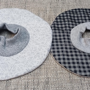 May include: Two fabric neck warmers, one with a white background and a gray floral pattern, and the other with a black and white checkered pattern.