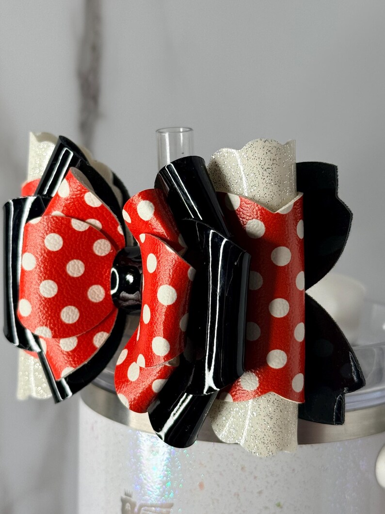 May include: A layered hair bow with a red polka dot design and white spots, black details, and glittery white edges. The bow has a glossy finish, suitable for various occasions.