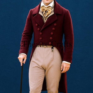 May include: A burgundy double-breasted coat with matching buttons, paired with tan trousers and a gold ascot. The coat has a long tail and is part of a historical costume. The text "Theatre Crafts" is visible.