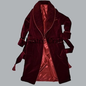 Könnte beinhalten: Ein burgunderfarbener Samtrobe mit gestepptem Kragen und Manschetten. Der Bademantel hat ein Satinfutter und einen passenden Gürtel mit Quasten. Der Text "Theatre Crafts" ist sichtbar.