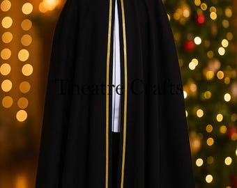 Puede incluir: Una capa negra con capucha, ribete dorado y forro interior blanco. La capa tiene un diseño fluido, adecuada para representaciones teatrales o eventos de disfraces. El texto "Theatre Crafts" es visible.