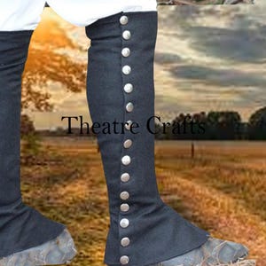 May include: Black leg coverings with silver-colored buttons, featuring the text "Theatre Crafts". The leg coverings appear to be made of a dark fabric and are designed to cover the lower leg.