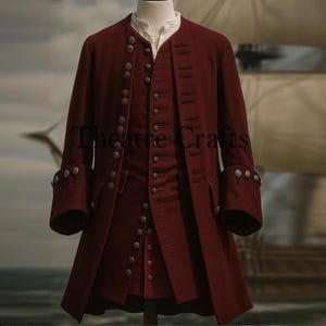 May include: A burgundy-colored, three-piece costume with multiple silver buttons. The long coat has large cuffs with silver buttons. The vest and coat are buttoned up. The text "Theatre Crafts" is visible on the coat.