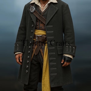 Puede incluir: Un abrigo largo gris oscuro con múltiples botones y cuello con solapas. El abrigo presenta un cinturón de cuero marrón y una faja amarilla. El texto "Theatre Crafts" es visible en el abrigo. El atuendo recuerda la vestimenta histórica o teatral.