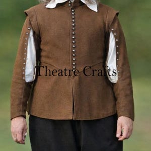 Puede incluir: Un jubón marrón con cuello alto, cuello de camisa blanco y mangas largas con tela blanca visible a través de aberturas laterales. La prenda tiene una fila vertical de pequeños botones metálicos en la parte delantera y el texto Theatre Crafts.