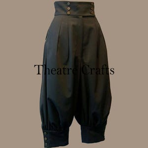 May include: Black high-waisted pants with a unique design. The pants feature a high waistband with three buttons, pleats, and gathered cuffs with button details. The text "Theatre Crafts" is visible on the pants.