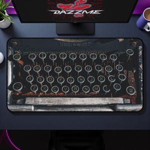 Könnte beinhalten: Rechteckiges Mauspad mit einem Vintage-Schreibmaschinen-Tastatur-Design. Die runden Tasten haben weiße Buchstaben auf schwarzem Hintergrund. Das Wort "UNDERWOOD" ist sichtbar. Das Mauspad liegt auf einer dunklen Oberfläche, mit einem Computermonitor und Zubehör im Hintergrund.