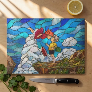 Könnte beinhalten: Ein rechteckiges Schneidebrett mit einer Illustration im Glasmalerei-Stil von zwei animierten Figuren. Der Hintergrund ist ein blauer Ozean und Himmel. Eine Figur fliegt, die andere steht auf einer Klippe. Ein Messer und eine Zitrone sind ebenfalls sichtbar.