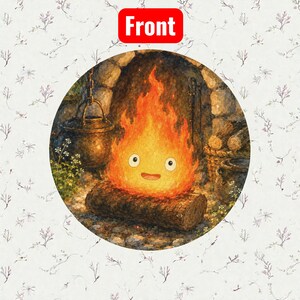 Pu&ograve; includere: Grafica rotonda con uno spirito del fuoco dei cartoni animati con un volto sorridente, fiamme e una base di tronco. Lo sfondo include un camino in pietra, una pentola appesa e un cesto di legno. La parola "Front" &egrave; in un rettangolo rosso.