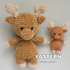 May include: Two plush, crocheted reindeer toys. The larger reindeer is brown with tan antlers and white accents on its hooves and paws. The smaller reindeer is also brown with tan antlers and white accents. The word "PATTERN" is printed on the bottom.