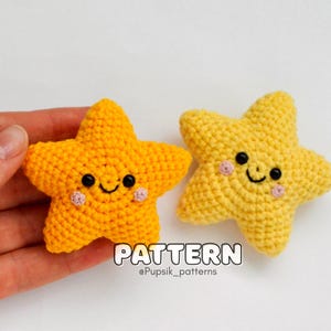 以下が含まれることがあります： 笑顔の顔をした、黄色い星形の編みぐるみが2つ。星は黒い目とピンクの頬をしています。星の真下に「PATTERN @Pupsík_patterns」という文字があります。