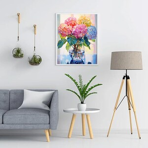 May include: A framed painting of a vibrant bouquet of hydrangeas in a clear glass vase. The flowers display a range of colors, including pink, orange, yellow, and blue. The painting is set against a soft, colorful background.