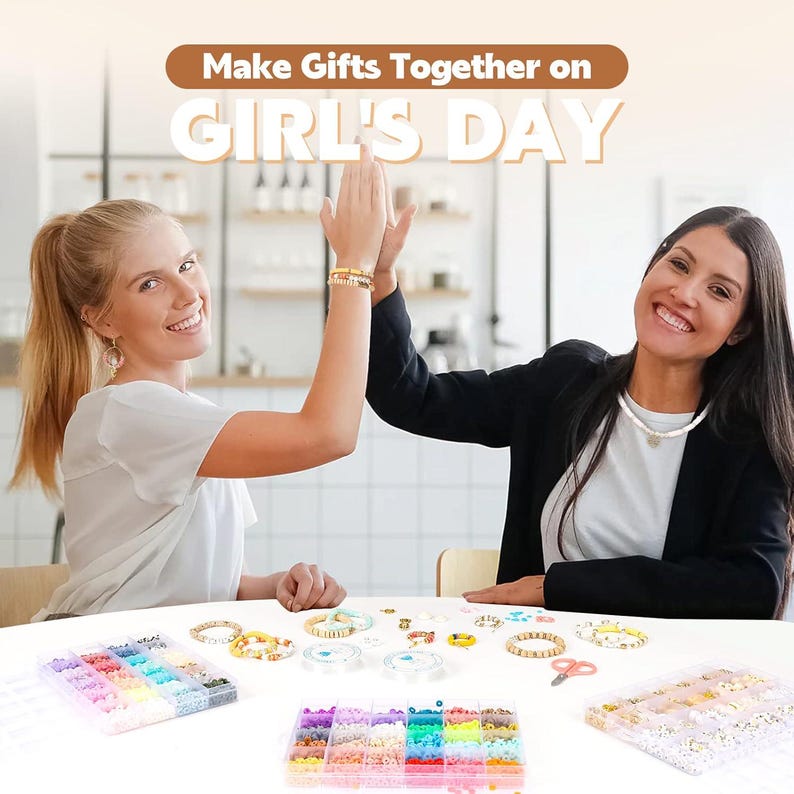 May include: Two women high-fiving over a table with jewellery-making supplies. The table displays colourful beads, bracelets, and tools. Text at the top reads "Make Gifts Together on GIRL'S DAY."