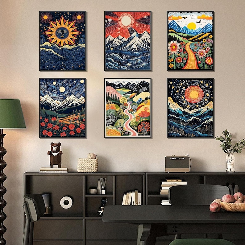 May include: Six framed art prints with colorful, stylized landscape scenes. Each print features a different mountain range, sun, moon, and stars. The color palette includes blues, oranges, and greens, creating a vibrant and whimsical aesthetic.