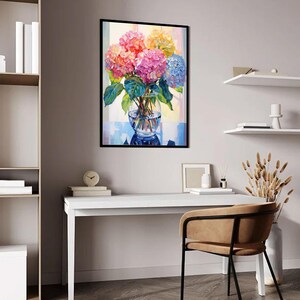 May include: A framed painting of colorful hydrangeas in a clear glass vase. The flowers are in shades of pink, orange, yellow, and blue, with green leaves. The painting is displayed on a white desk with a chair.