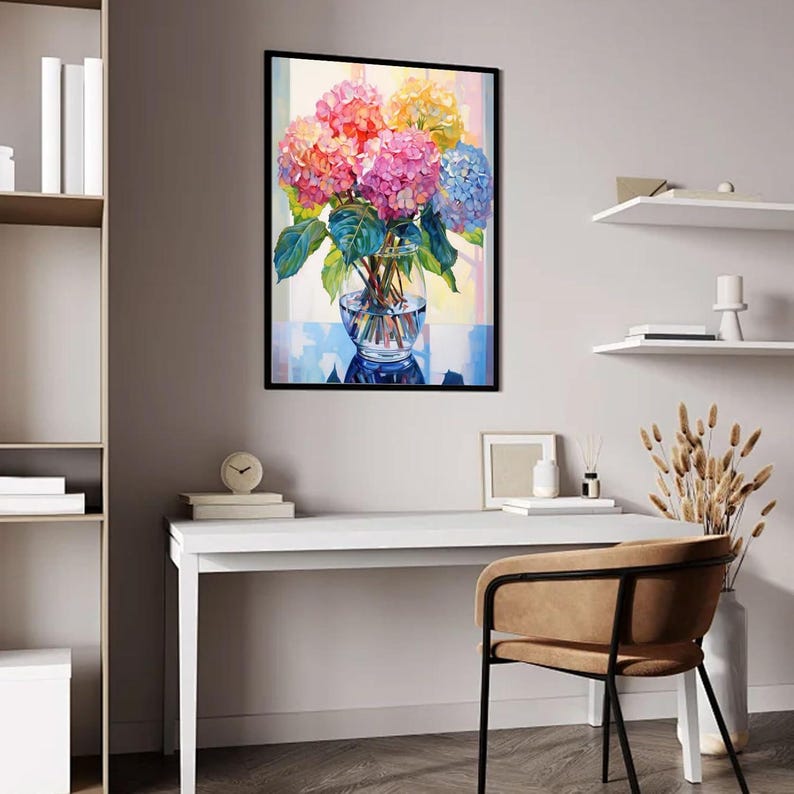 May include: A framed painting of colorful hydrangeas in a clear glass vase. The flowers are in shades of pink, orange, yellow, and blue, with green leaves. The painting is displayed on a white desk with a chair.
