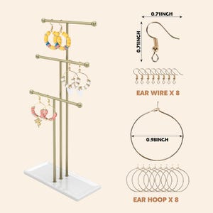 May include: A gold-coloured earring display stand with three tiers, holding various earrings. The stand has a white base. The image also shows ear wires (1.8 cm) and ear hoops (2.5 cm).