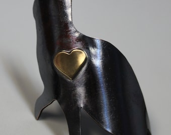 May include: A black metal cat sculpture with a gold heart on its side. The sculpture is made of metal and has a rustic finish.