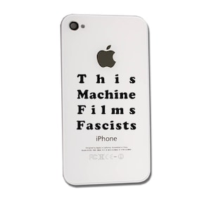 May include: White iPhone with an apple logo and the text "This Machine Films Fascists" on the back.