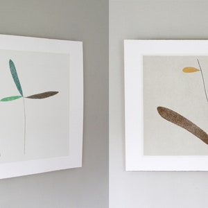 May include: Two framed abstract art prints with minimalist line drawings of stylized plants in shades of green, blue, brown, pink, and yellow on a white background.