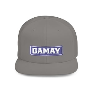 May include: A gray baseball cap with a flat brim. The cap features the word "GAMAY" embroidered in white letters on a blue rectangular patch.