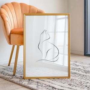 Puede incluir: Una lámina de arte mural rectangular en un marco dorado fino con un dibujo de línea continua negra de un gato sentado sobre un fondo blanco. La obra de arte se muestra en posición vertical, destacando la silueta felina sobre el papel blanco.