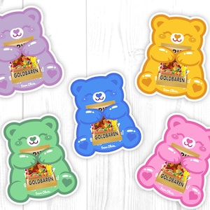 May include: A collection of colorful bear-shaped stickers. Each sticker features a cartoon bear holding a package of Goldbaren gummy candies. The bears are in shades of purple, blue, green, yellow, and pink. The text "Goldbaren" is visible on the candy package.