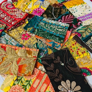 May include: A collection of colorful fabric patches with intricate embroidery and embellishments. The patches feature a variety of colors, including red, yellow, green, and orange, with gold and silver metallic threads. Floral and geometric patterns are visible.