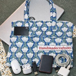 May include: A blue and white floral patterned tote bag with a laptop inside. The bag has a pocket with a black external hard drive. Other items include a white mouse, earbuds, USB drives, and a charger.