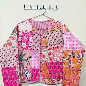 Puede incluir: Chaqueta patchwork rosa con diversos estampados florales y geométricos. La chaqueta tiene cuello en V, mangas largas y cierre de botones. El diseño incorpora diversas texturas e impresiones de tela, creando una prenda única y colorida.