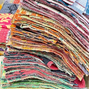Peut inclure: Un empilement de chutes de tissu colorées avec divers motifs et couleurs, notamment orange, rouge, vert et bleu. Les bords du tissu sont effilochés, suggérant une qualité vintage ou faite à la main. Les textiles semblent être recyclés ou surcyclés.