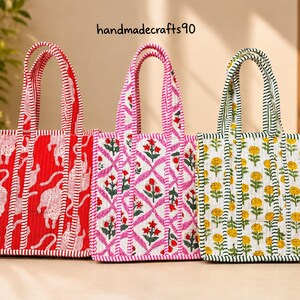 Op de afbeelding: Drie gewatteerde draagtassen met verticaal gestreepte hengsels. De linker tas is rood met witte tijgerpatronen. De middelste tas is wit met een roze ruit- en bloemenprint. De rechter tas is wit met gele bloemenpatronen. Tekst: handmadecrafts90.