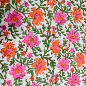 May include: White fabric with a repeating floral pattern. The design features pink and orange flowers with green stems and leaves. Small pink flowers are scattered throughout the design.