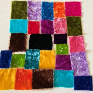 Może przedstawiać: Kolekcja kolorowych próbek tkanin welurowych w różnych odcieniach, w tym zielonym, fioletowym, niebieskim, pomarańczowym i różowym. Próbki są ułożone w siatkę, prezentując teksturę i wariacje kolorystyczne tkaniny.