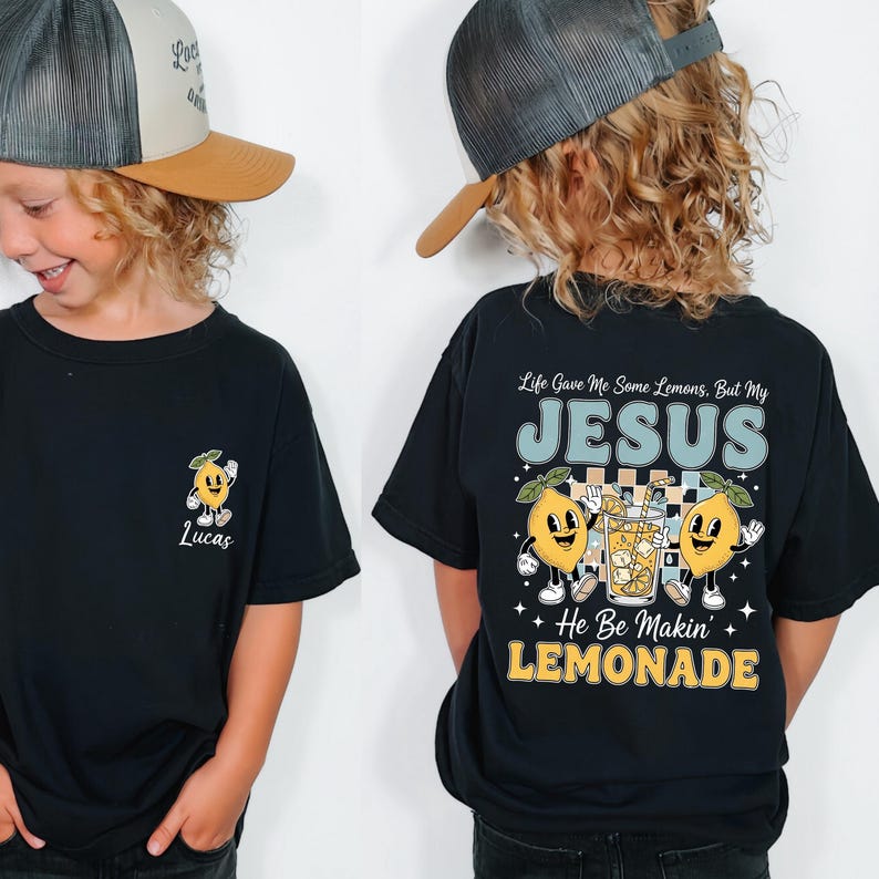 A young boy wearing a black t-shirt with a graphic design and text on the back, smiling and looking at the camera.