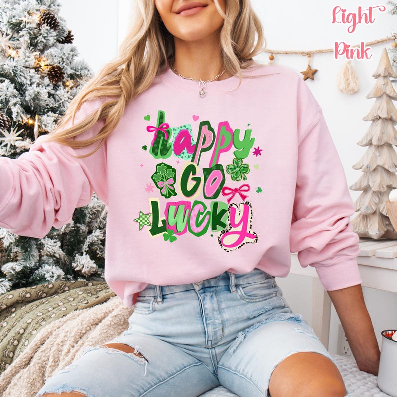 A woman wearing a pink sweatshirt with a colorful graphic design that says "Happy Go Lucky" on it.
